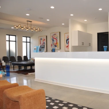 Reception area at Pappas Orthodontics showcasing modern decor, front desk, seating, and bright lights.