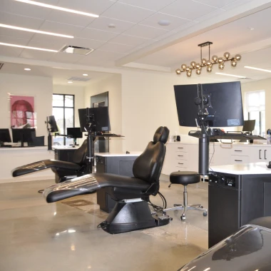 Orthodontic treatment area featuring sleek dental chairs, technology, bright lighting, and open layout.